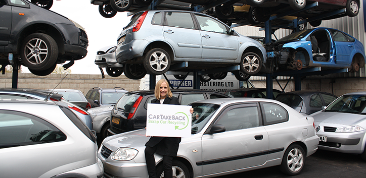 CarTakeBack logo being held by staff member in front of scrap car recycling centre
