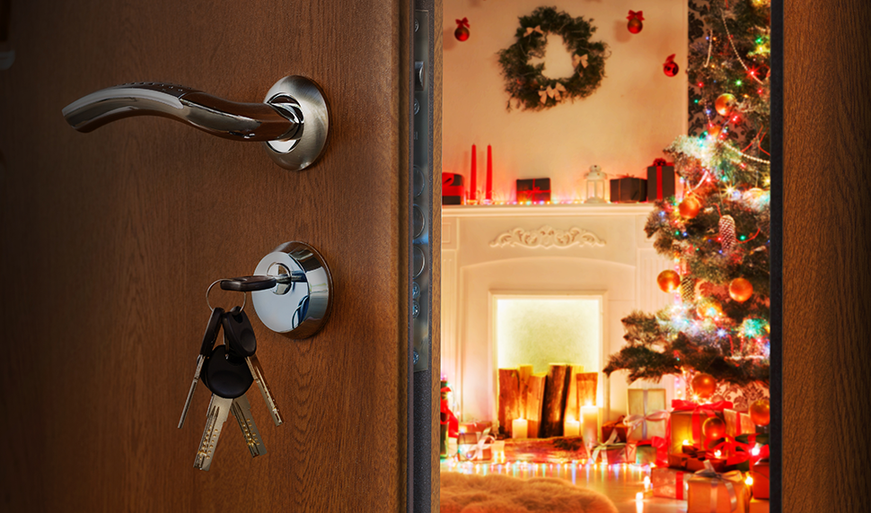 Keys in a door lock with the door ajar, the interior can be seen with Christmas decorations